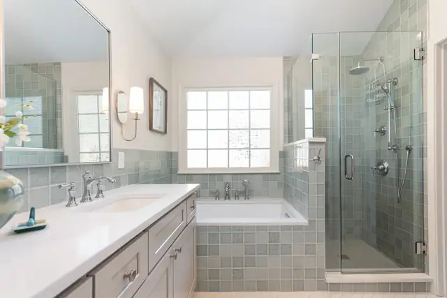 Bathroom with a gray vanity, a tiled soaking tub, a frameless glass shower and sage green wall tile by Ironwood Custom Remodels