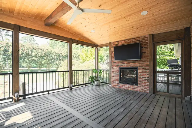 Screened porch with a wood plank ceiling, a brick fireplace, a mounted TV and composite decking