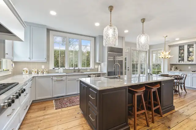 Hurdle Mills kitchen with light cabinets, a dark wood island with a stone top, glass pendant lights and resurfaced pine floors by Ironwood Custom Remodels