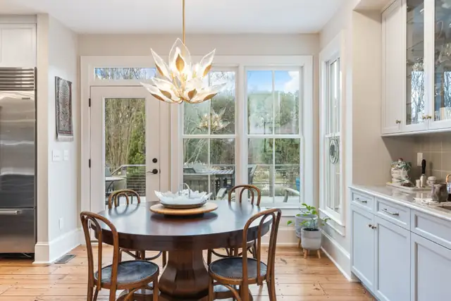 Breakfast nook with a round wood table, bentwood chairs and a lotus chandelier beside glass doors in a Hurdle Mills kitchen