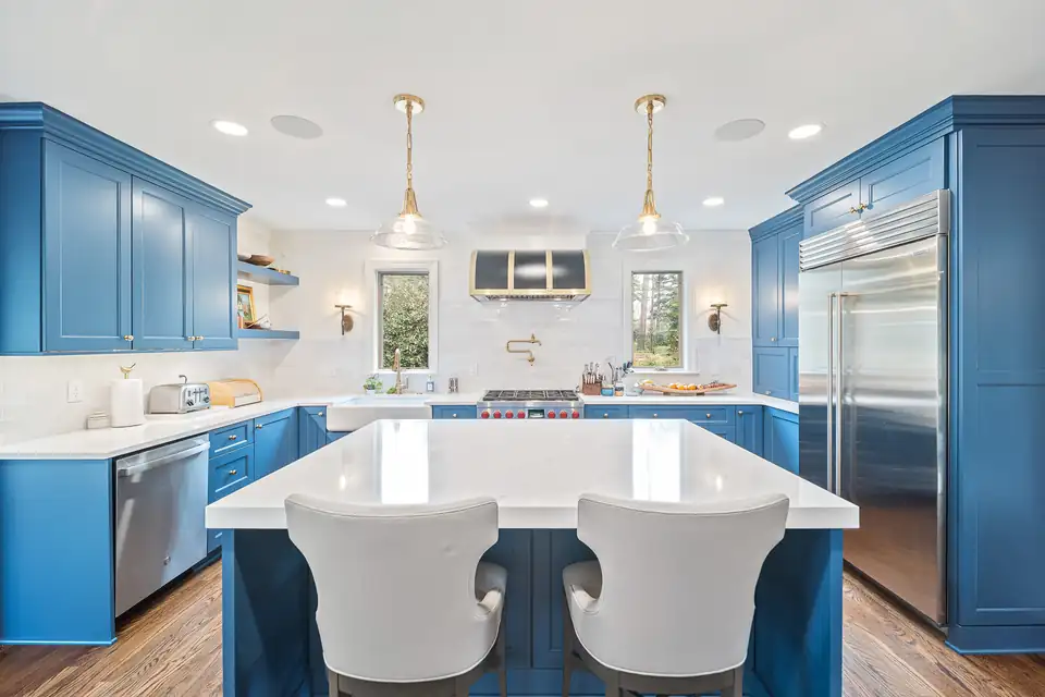 Kitchen remodeling in Durham, NC: blue cabinets, white counters, an island with white stools and a Sub-Zero refrigerator in Hope Valley by Ironwood Custom Remodels